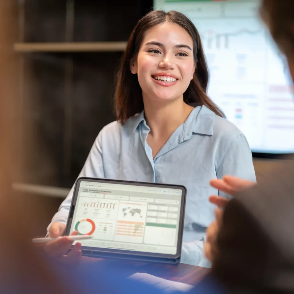 A person holds a tablet displaying graphs and charts during a meeting.