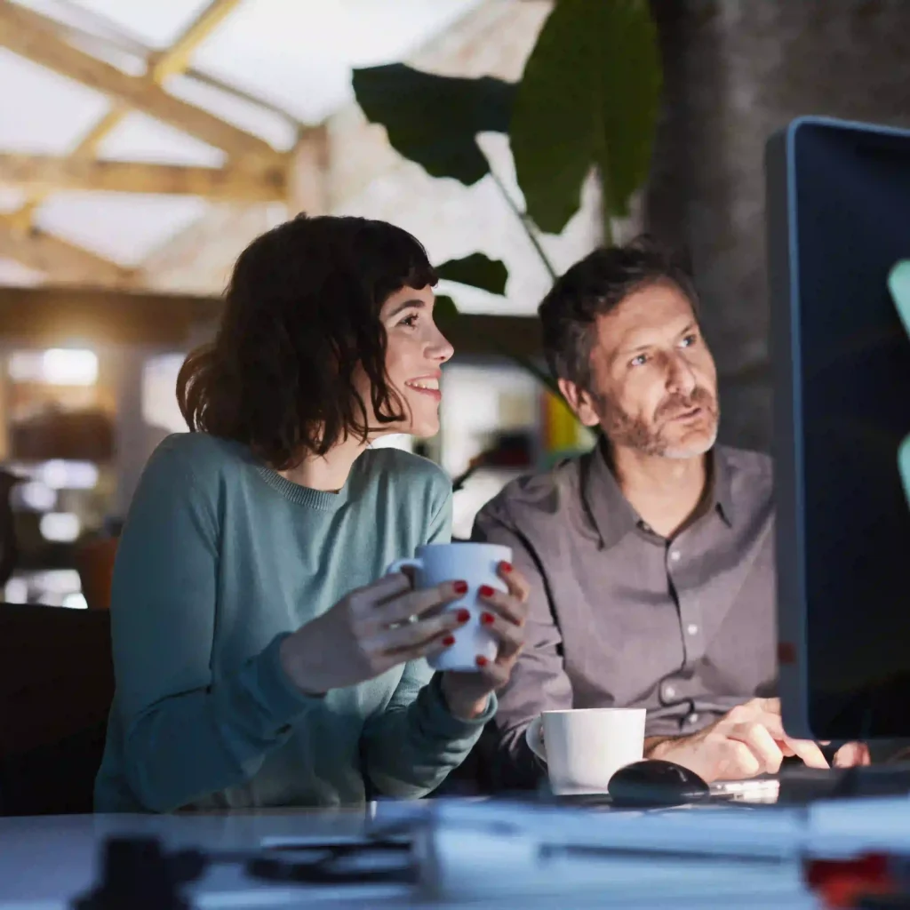 Two people, a woman and a man, sitting in front of a monitor.